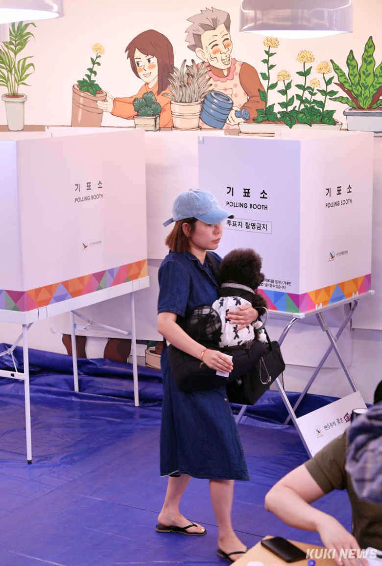 제21대 대통령 선거일인 3일 서울 강동구 강풀만화거리 만화카페 승룡이네에 마련된 성내2동제3투표소에서 유권자가 반려견을 안고 투표함으로 향하고 있다.