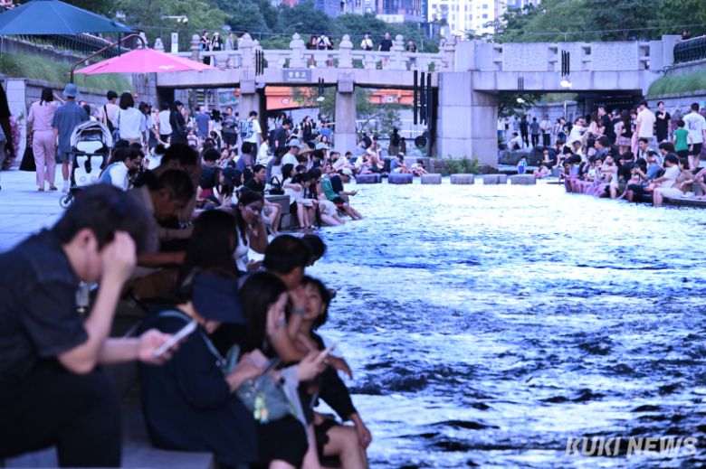 가마솥 더위가 이어지고 있는 가운데 휴일인 12일 저녁 서울 중구 청계천을 찾은 많은 시민들이 흐르는 천에 발을 담그고 더위를 식히고 있다.