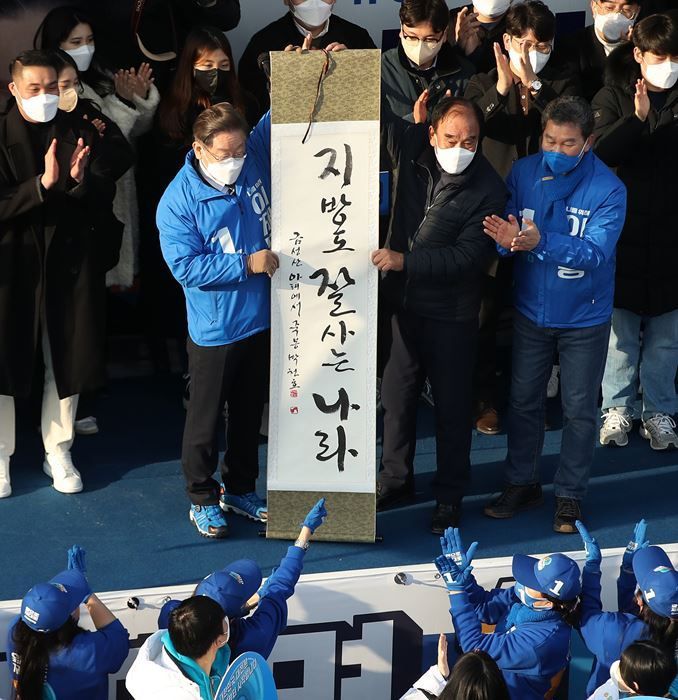 지난 2월18일, 이재명 당시 더불어민주당 대선후보가 전남 나주시 금성관 정수루에서 ‘지방도 잘 사는 나라’라는 휘호가 담긴 족자를 선물받고 있다. ⓒ뉴시스