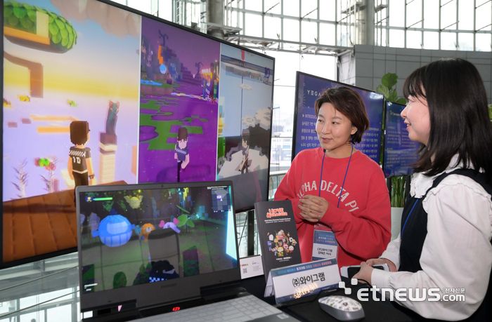 14일 서울 강남구 코엑스 스튜디오159에 마련된 와이그램 부스에서 참석자가 인공지능(AI) 캐릭터를 활용한 게임 중계 방식의 유저참여형 애니메이션 '메타애니메이션'에 대한 설명을 듣고 있다. 김민수기자 mskim@etnews.com