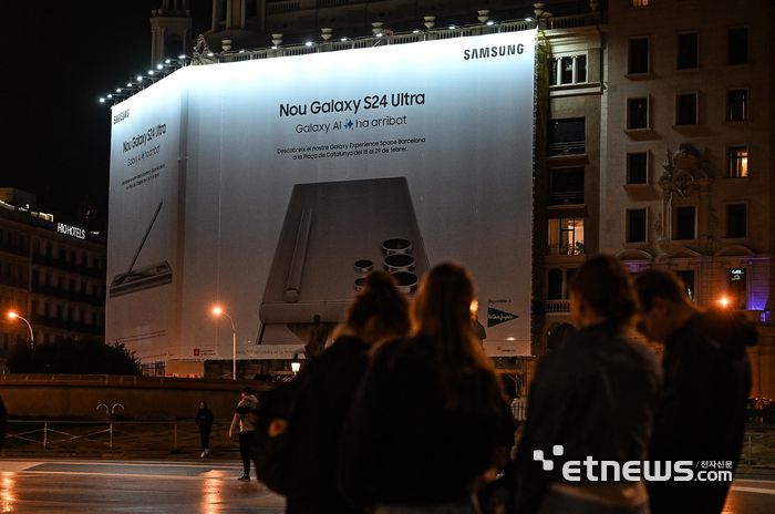 스페인 바르셀로나에서 열리는 세계 최대 이동통신 박람회 모바일 월드 콩그레스 (MWC) 2024 개막을 사흘 앞둔 23일(현지시간) 밤 카탈루냐 광장 인근 건물 외벽에 삼성 갤럭시S24 대형 옥외 광고물이 내걸려 있다. 삼성전자는 MWC2024 개막에 맞춰 삼성전자는 스페인 바르셀로나의 중심지 카탈루냐 광장에서 갤럭시S24 시리즈를 체험할 수 있는 '갤럭시 익스피리언스 스페이스' 체험관을 29일까지 운영한다. 바르셀로나(스페인)=이동근기자 foto@etnews.com