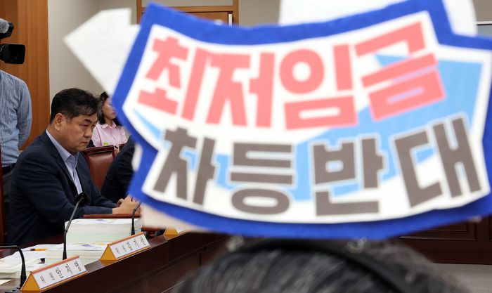 19일 정부세종청사에서 열린 최저임금위원회 제6차 전원회의에서 한 근로자위원이 '최저임금 차등반대'라는 머리띠를 한 가운데 이인재 위원장이 생각에 잠겨 있다. 연합뉴스.