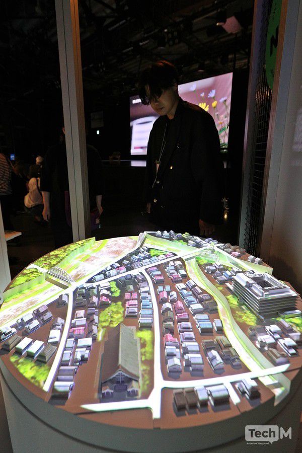 지난달 10일 일본 '2025 오사카·간사이 엑스포'에 마련된 네이버클라우드 전시관 내부에서 한 스태프가 도심지를 구현한 디지털트윈 코너 모형을 살펴보고 있다. /사진=임경호 기자