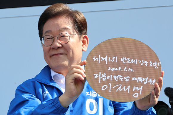 이재명 대통령(당시 대선 후보)이 6·3 대통령선거 공식 선거운동 첫날인 지난 5월 12일 경기 화성시 동탄 센트럴파크 음악분수중앙광장 유세장에서 '세계1위 반도체 강국 도약!'이라고 쓰고 서명한 반도체 웨이퍼를 들어보이고 있다. [사진=연합뉴스]