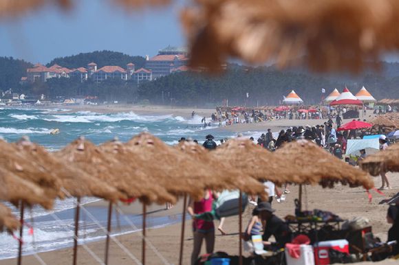 가림막 아래서 더위를 피하는 여름 휴가지의 사람들. [사진=연합뉴스]