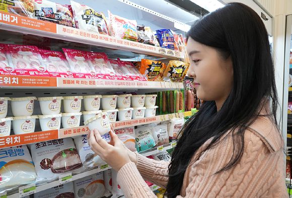 모델이 세븐일레븐에서 일본 직소싱 상품인 '저지우유푸딩'을 살펴보고 있다. [사진=세븐일레븐]