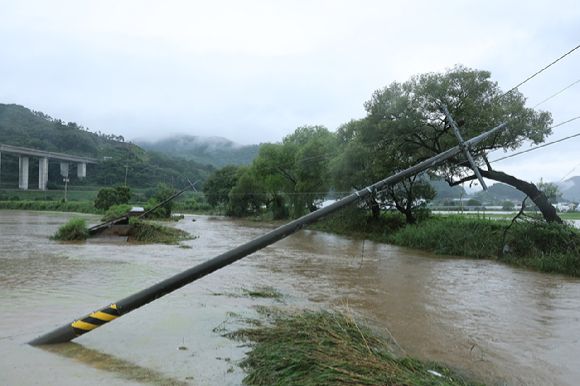 지난 17일 호우특보가 내려진 충남 공주시 사곡면에서 한 도로가 무너져 내렸고 전봇대가 위태롭게 쓰러져 있다.  [사진=연합뉴스]