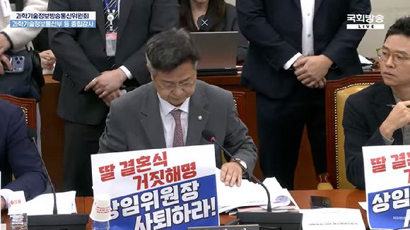국민의힘 과방위원들이 29일 국정감사에서 '딸 결혼식 거짓 해명, 행정실 직원 갑질, 상임위원장 사퇴하라'는 피켓을 앞에 두고 최 위원장 사퇴를 요구하고 있다. [사진=국회방송]