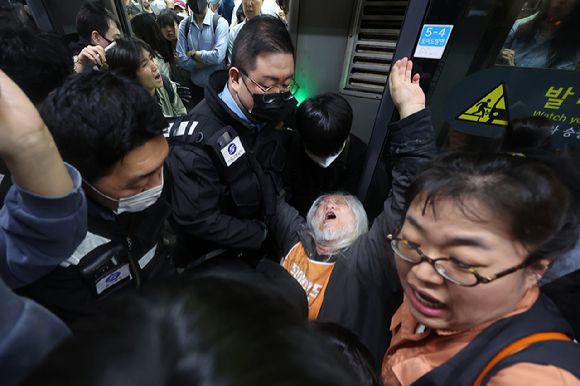 박경석 전국장애인차별철폐연대(전장연) 대표가 지난해 4월 21일 서울 지하철 4호선 혜화역에서 제62차 '출근길 지하철 탑니다' 시위를 벌이던 중 이를 저지하던 서울교통공사 관계자와 충돌하고 있다. [사진=연합뉴스]