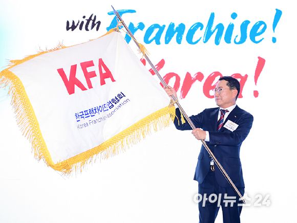 나명석 신임 한국프랜차이즈산업협회장(웰빙푸드 회장)이 19일 오후 서울 여의도 콘래드 서울 그랜드볼룸에서 열린 한국프랜차이즈산업협회 협회장 이·취임식 및 비전 선포식에서 협회기를 흔들고 있다. [사진=정소희 기자]