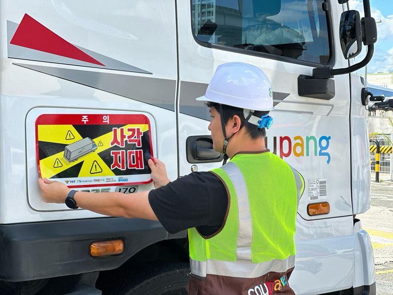 쿠팡·쿠팡로지스틱스서비스 대형 화물차에 '사각지대 주의' 알림 표지를 부착하는 모습. 사진ㅣ쿠팡