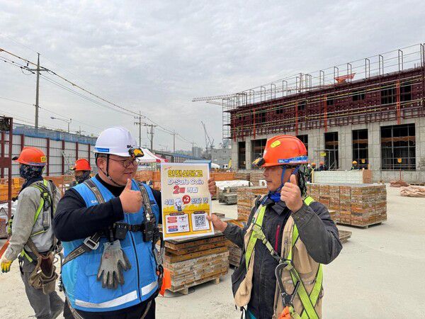 DL이앤씨 현장 안전관리자가 근로자에게 안전신문고 활성화 캠페인에 대해 설명하고 있다.