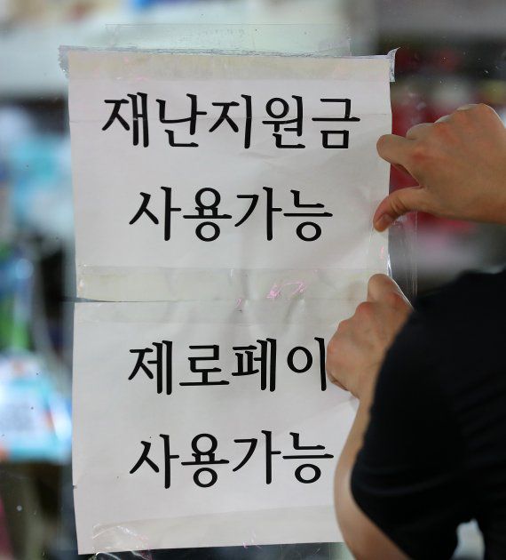 정부가 코로나 상생 국민지원금 세부시행계획을 발표한 30일 오후 서울 마포구 공덕역 인근 식당 주인이 재난지원금 사용 가능 안내문을 붙이고 있다. 뉴시스