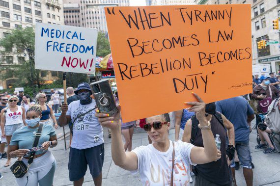 미국의 코로나19 백신 부스터샷 접종 일정이 늦춰질 것으로 예상되는 가운데 지난달 25일(현지시간) 뉴욕에서 백신접종 의무화에 반대하는 이들이 시위를 하고 있다. 한 여성이 백신접종 의무화를 독재라고 규정하고 "독재가 법이 되면 반란은 의무가 된다"는 문구가 새겨진 팻말을 들고 있다. AP뉴시스