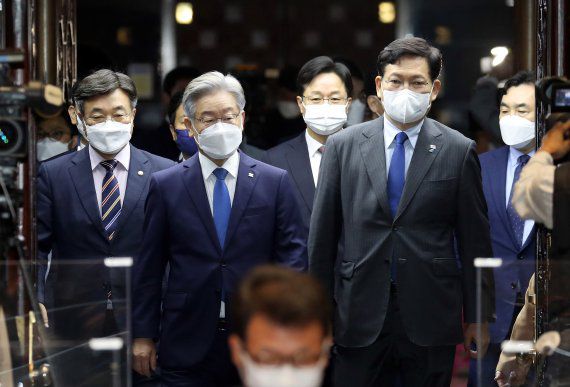 이재명 대선 후보가 15일 오전 서울 여의도 국회 예결위회의장에서 열린 더불어민주당 의원총회에서 당 지도부와 함께 입장하고 있다. 2021.10.15/뉴스1.                                    16일 오후 국민의 힘 이준석 당 대표가 경남 창원시 마산합포구 인근 도로에서 대장동 게이트 특검 촉구 1인 도보 피케팅을 하고 있다. 뉴시스.