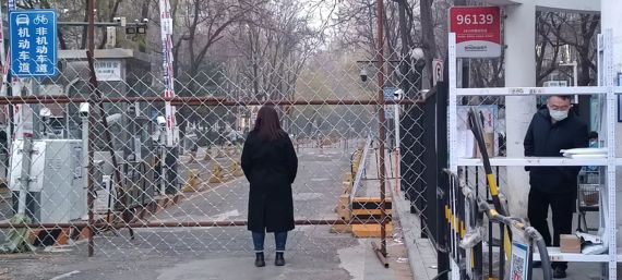 25일 오전 중국 베이징 차오양구 왕징의 한 아파트 바리케이드 입구에서 주민이 봉쇄 지역 안을 바라보고 있다. 사진=정지우 특파원