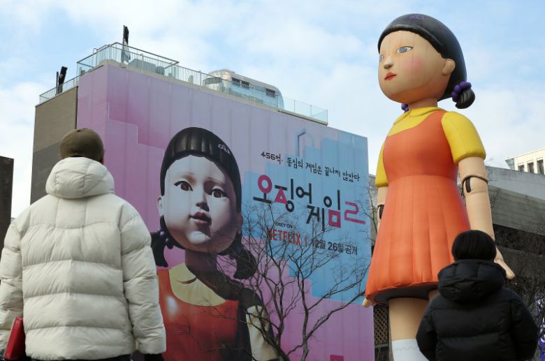 지난 29일 오후 서울 종로구 광화문광장을 찾은 시민들이 넷플릭스 오리지널 시리즈 '오징어게임2' 광고와 '영희'의 대형 조형물을 바라보고 있다. 뉴스1
