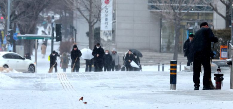 수도권 지역에 눈이 내린 지난 7일 오전 인천 남동구 시청입구 삼거리에서 한 건물 관계자가 인도의 눈을 쓸고 있다. 뉴시스 제공
