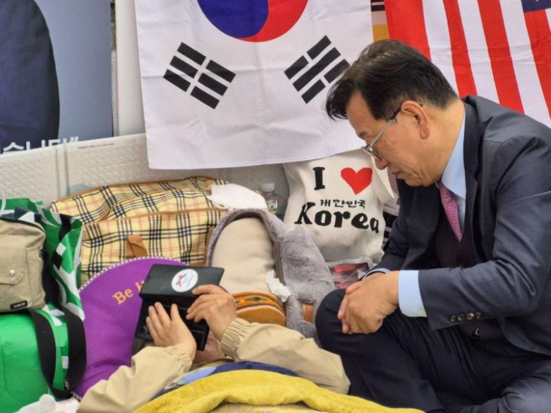 28일째 헌법재판소 앞에서 탄핵반대 단식투쟁을 하던 전지영 자유정의실천연합 국장(왼쪽)이 25일 윤석열 대통령과 통화하는 모습. 윤 대통령 측 변호인단 석동현 변호사(오른쪽)는 이날 전 국장을 찾아 윤 대통령과 통화를 연결했고, 이날 통화에서 윤 대통령은 전 국장의 단식 중단을 거듭 촉구했다.