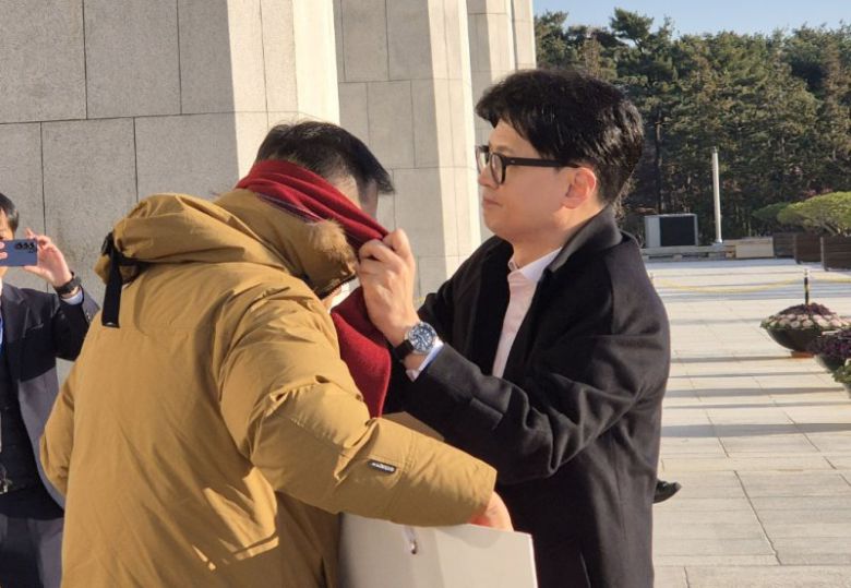 한동훈 국민의힘 대표가 지난해 12월14일 오전 서울 여의도 국회로 출근하며 윤석열 대통령 탄핵 촉구 1인 시위를 하고 있는 김상욱 의원에게 자신의 목도리를 건네주고 있다. /사진=김상욱 의원실 제공,뉴시스