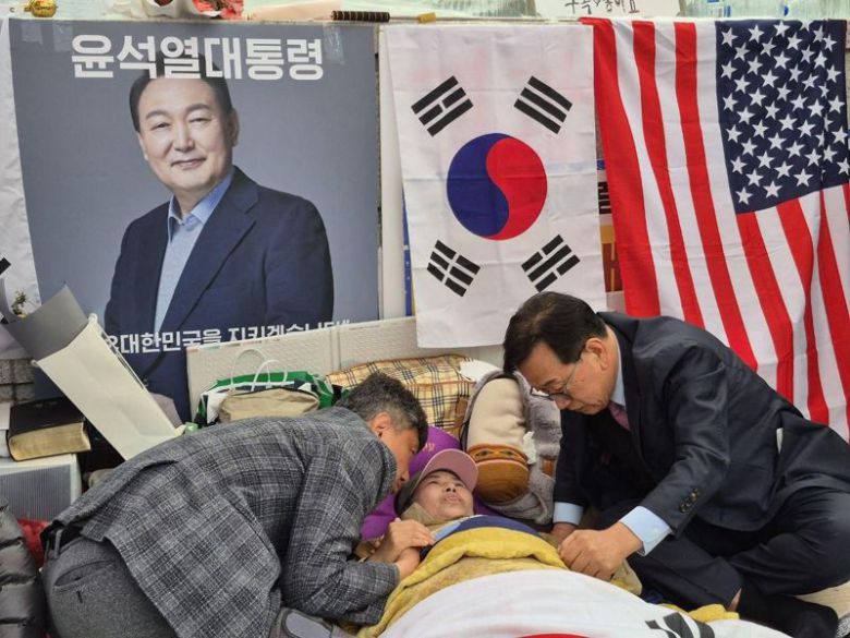 28일째 헌법재판소 앞에서 탄핵반대 단식투쟁을 하던 전지영 자유정의실천연합 국장(가운데)을 25일 찾아간 윤석열 대통령 측 변호인단 석동현 변호사(오른쪽)가 전 국장 손을 잡고 격려하고 있다.