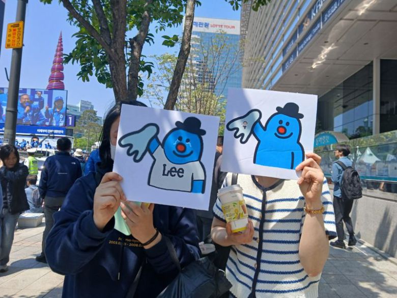 12일 서울 중구 광화문 청계광장에서 만난 민주당 지지자들이 이재명 더불어민주당 후보의 영문 성인 'Lee'를 캐릭터화한 그림을 들고 있다. 사진=송지원 기자