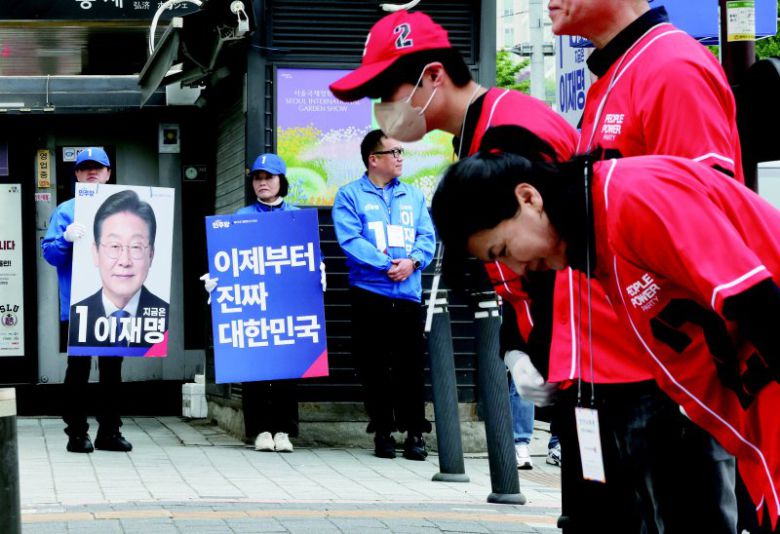 제21대 대통령 공식 선거운동 둘째날인 13일 서울 서대문구 한 거리에서 이재명 더불어민주당 후보와 김문수 국민의힘 후보 선거운동원들이 시민들에게 인사하고 있다. 연합뉴스
