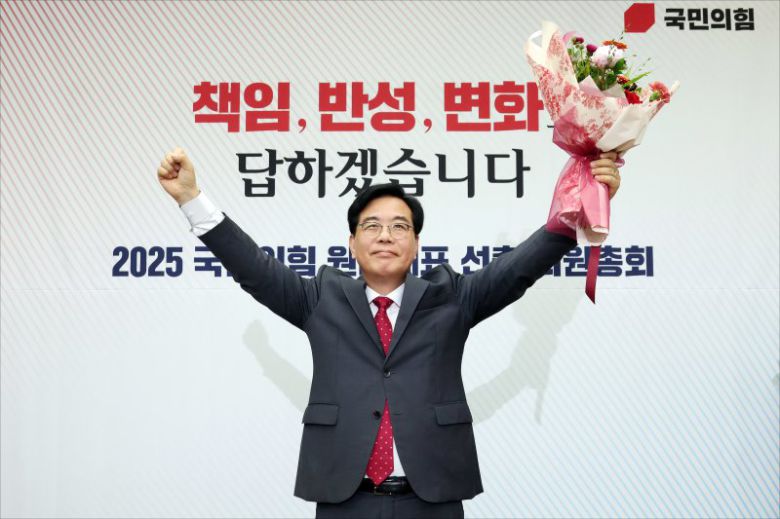송언석 국민의힘 신임 원내대표가 지난 16일 서울 여의도 국회에서 열린 2025 국민의힘 원내대표 선출 의원총회에서 꽃다발을 든 채 손을 들어올리고 있다. 뉴스1