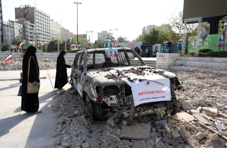 23일(현지시간) 이란 수도 테헤란에서 시민들이 이스라엘의 공습으로 파괴된 이란 적신월사의 구급차를 바라보고 있다.EPA연합뉴스