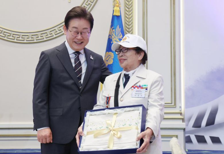이재명 대통령이 27일 청와대 영빈관에서 열린 '호국보훈의 달, 대통령의 초대' 행사에서 특별초청 대상자인 6·25전쟁 참전유공자 이춘자 참전용사에게 광목이불 선물을 전달 후 미소짓고 있다. 대통령실통신사진기자단