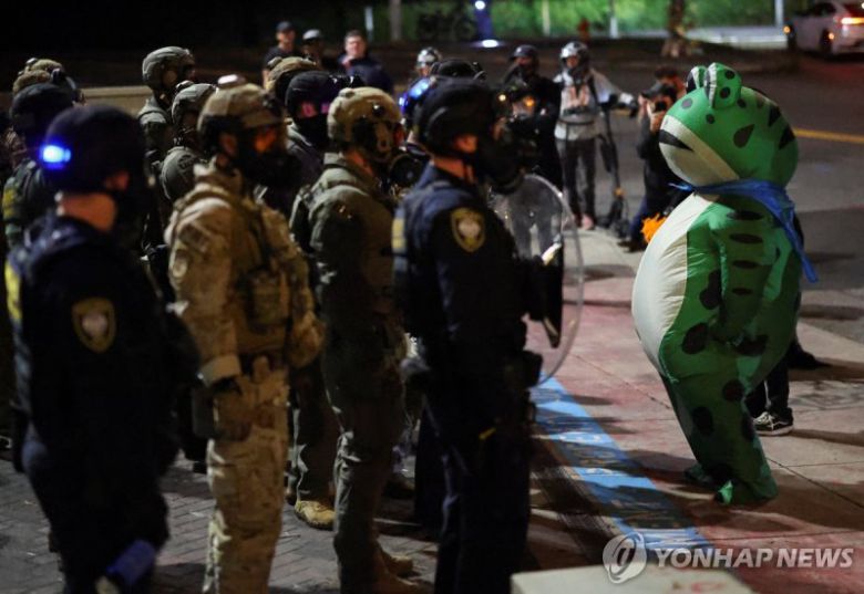 포틀랜드에서 개구리 복장으로 ICE 요원과 대치 중인 한 시위자.연합뉴스