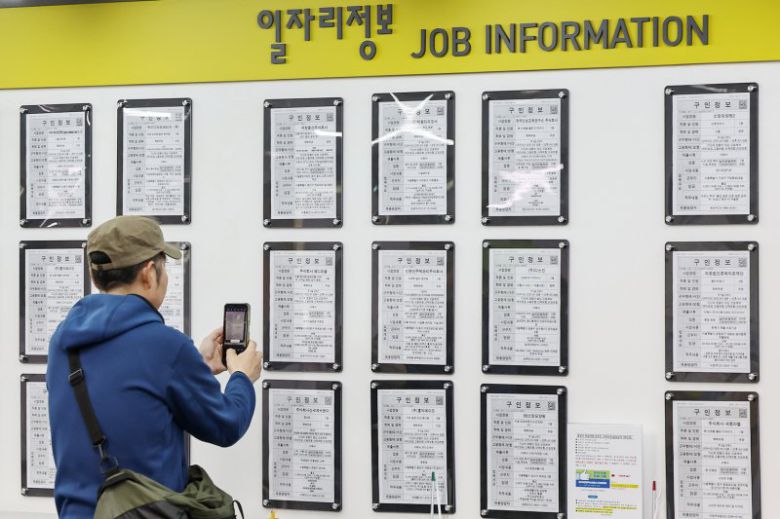 지난 13일 서울 마포구 서부고용복지플러스센터에서 한 구직자가 일자리 정보 게시판 속 구인업체 정보를 휴대전화 카메라에 담고 있다. 뉴스1