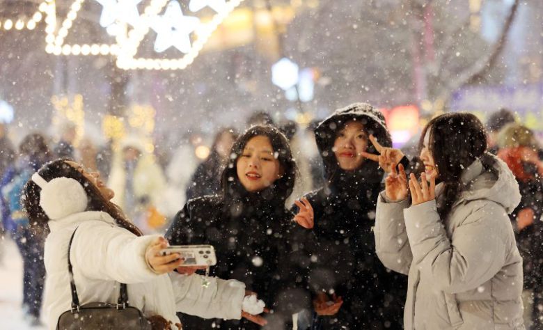 지난 4일 서울 마포구 홍대 부근에 눈이 내리는 가운데 외국인 관광객들이 기념사진을 촬영하고 있다. 연합뉴스