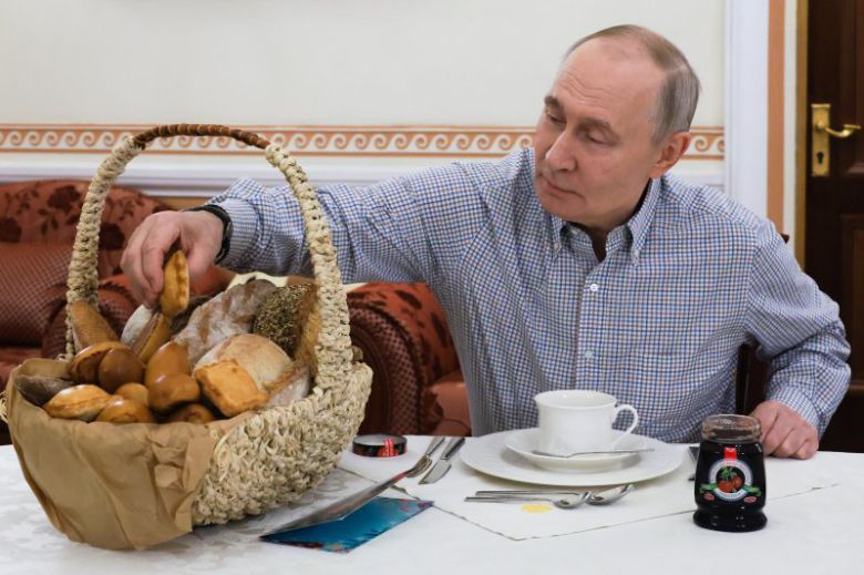 러시아의 블라디미르 푸틴 대통령이 20일(현지시간) 러시아 모스크바에서 전날 연례 기자회견 중 언급한 류베르치 '마셴카' 제과점의 빵을 꺼내고 있다.AP연합뉴스