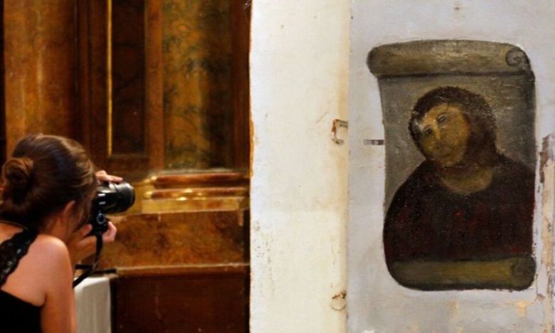 스페인 북동부에 있는 보르하 마을 교회에서 19세기 화가 엘리아스 가르시아 마르티네스의 작품 '에케 호모'의 복원화 앞에서 한 여성이 사진을 찍고 있다. AFP연합뉴스