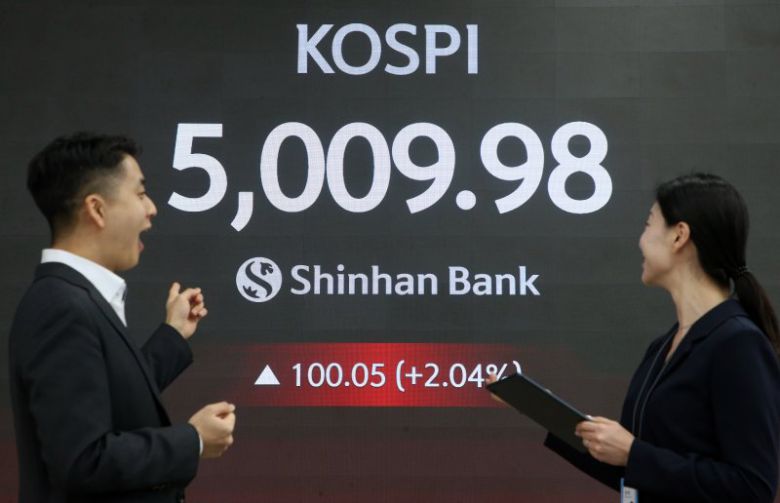 코스피가 장중 5000을 넘어선 가운데 22일 서울 중구 신한은행 본점 로비에서 딜러들이 미소 짓고 있다. 신한투자증권 제공