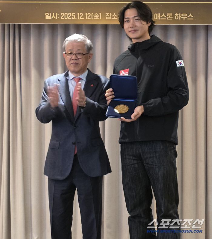 최신원 대한펜싱협회장이 오상욱에게 국제펜싱연맹(FIE) 명예의 전당 상패를 전달한 후 박수를 치며 축하하는 모습.