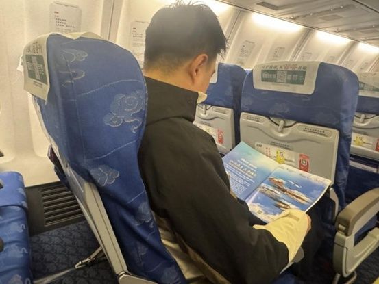 한·중 이중언어 잡지 <진챠오>의 특집 지면을 읽고 있는 승객 [사진=산둥항공]