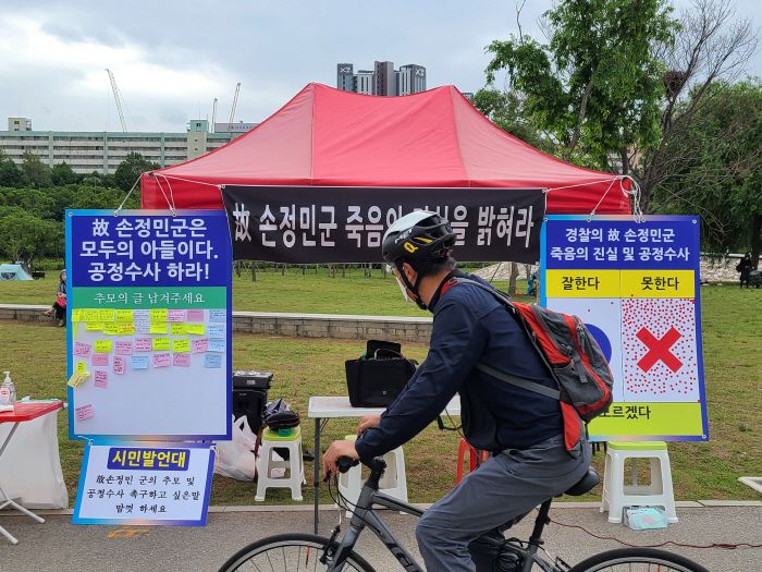 29일 오후 서울 서초구 반포한강공원 수상택시 승강장 인근에 설치된 `고(故) 손정민씨 추모·공정수사 촉구 시민 발언대`를 지나가는 시민이 살펴보고 있다. [사진 출처 = 연합뉴스]