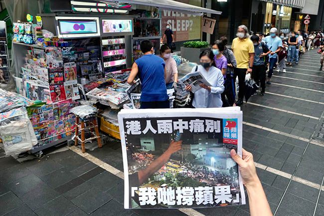 홍콩의 대표적 반중매체 빈과일보의 폐간 전 `마지막 신문`을 사려는 시민들이 지난 6월 24일 시내 가판대 앞에 길게 줄지어 서 있는 가운데 한 여성이 폐간호 1면을 들어 보이고 있다. 빈과일보는 국가보안법(홍콩보안법) 시행 1주년을 엿새 앞두고 이날 마지막 신문을 발행하며 창간 26년의 역사를 마감했다. /사진=홍콩 AP 연합뉴스