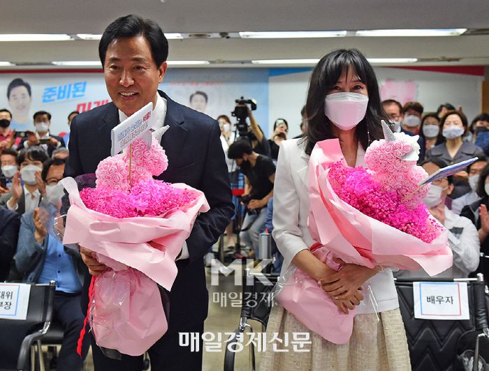 오세훈 시장이 지난 6월 2일 캠프 개표상황실에서 당선이 확실시되자 부인 송현옥 씨와 꽃다발을 받고 기뻐하는 모습. 뉴진스와 기념 촬영할 때보다는 웃음의 강도가 약해 보인다. [매경db]
