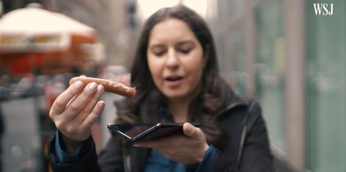 월스트리트저널(WSJ)의 테크 칼럼니스트 조안나 스턴이 삼성 폴더블폰 ‘갤럭시 폴드’에 소시지를 끼워 넣으면서 조롱하고 있다. [사진 출처 = 월스트리트저널 유튜브 영상 갈무리]