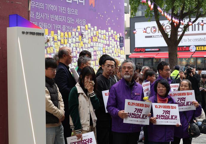 10·29 이태원 참사 유가족협의회와 10·29 이태원 참사 시민대책회의가 26일 오전 서울 용산구 이태원역 1번 출구 앞에서 기자회견을 열어 해밀톤호텔 옆 골목을 ‘10·29 기억과 안전의 길’이라 이름 붙이고, 3개의 빌보드 등 시설물을 설치하는 것을 뼈대로 한 ‘참사 현장’ 정비 내용을 기자들에게 설명하는 동안 참가자들이 골목을 바라보고 있다. [사진 출처=연합뉴스]