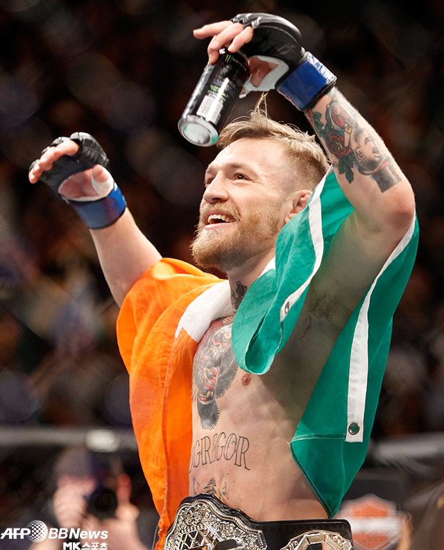 잠정 챔피언 코너 맥그레거가 2015년 12월 UFC 페더급 통합타이틀매치 승리로 정규 챔피언이 되자 아일랜드 국기를 어깨에 멘 채 기뻐하고 있다. 사진=AFPBBNews=News1