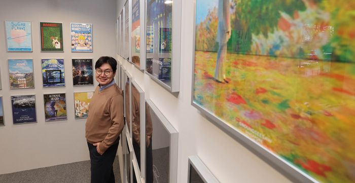 지성욱 미디어앤아트 대표가 역대 전시 포스터들이 전시된 사무실 공간에서 환하게 웃어 보이고 있다. 이충우 기자