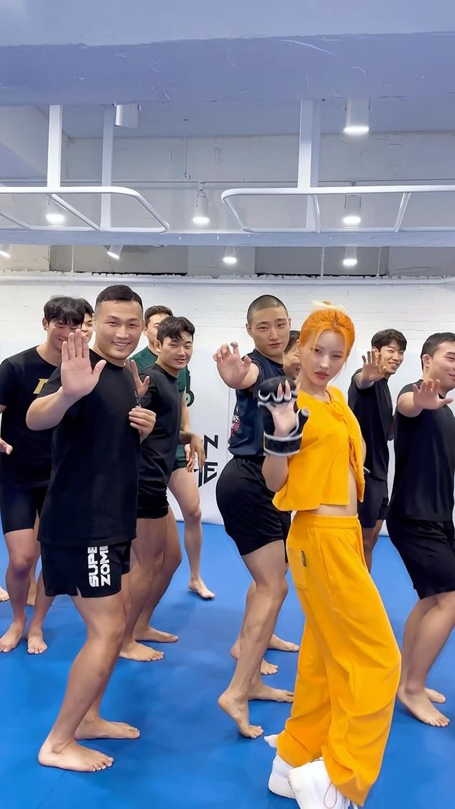 종합격투기 글러브를 착용한 소연(앞줄 오른쪽)이 여자아이들 미니 앨범 7집 타이틀 ‘클락션’ 홍보를 위한 안무 영상을 정찬성(앞줄 왼쪽) 및 코리안좀비MMA 체육관 제자들과 함께 촬영하고 있다. 사진=큐브엔터테인먼트/카카오엔터테인먼트