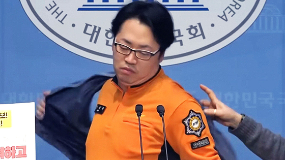 김성현 전국공무원노조 서울소방지부 구급국장이 지난 17일 국회의원회관에서 열린 기자회견에서 왜곡 우려에 노조조끼를 벗고 있다. [사진 = MBC 캡처]