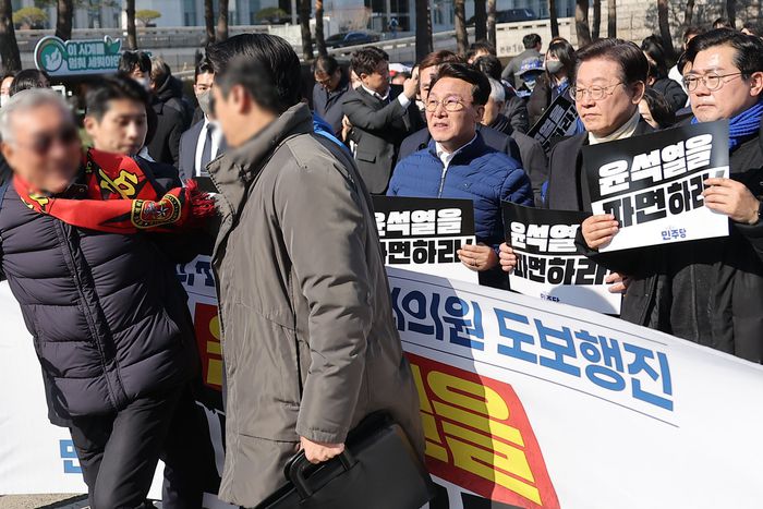 지난 19일 국회에서 열린 윤석열 대통령 파면 촉구 국회의원 도보행진에서 한 참가자가 이재명 더불어민주당 대표에게 다가가자 경찰과 경호 인력이 이를 제지하고 있다. [사진 출처 = 연합뉴스]