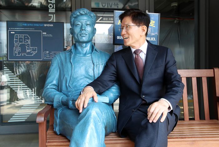 김문수 전 고용노동부 장관이 10일 서울 종로구 전태일기념관에 설치된 전태일 동상 옆에 앉아 있다.  [사진출처 = 공동취재]