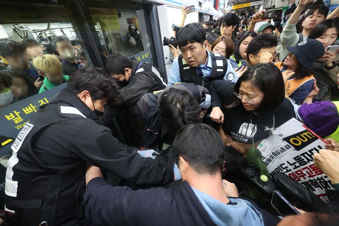 전국장애인차별철폐연대(전장연) 회원들이 21일 서울 지하철 4호선 혜화역에서 제62차 ‘출근길 지하철 탑니다’ 시위를 벌이던 중 지하철 탑승을 시도하며 서울교통공사 직원들과 충돌하고 있다. [연합뉴스]